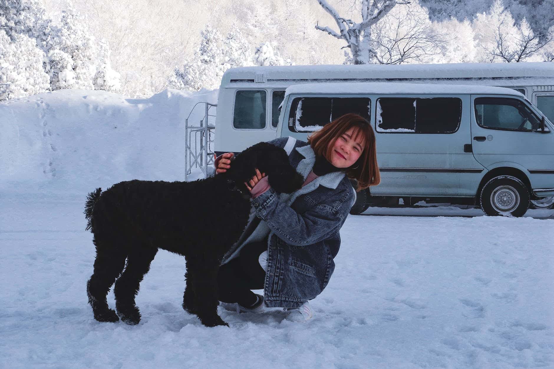 woman hugging short coated black dog